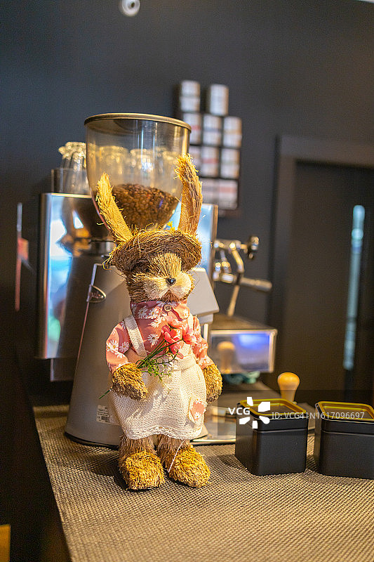 咖啡店里穿着连衣裙和草帽的玩具兔子：复活节、春天和餐厅装饰图片素材