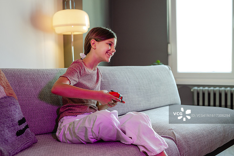 可爱女孩在家玩电子游戏的侧面图图片素材