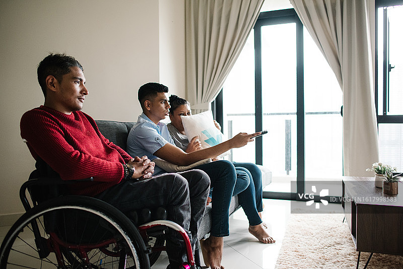 亚洲马来残疾人士与朋友一起看电视图片素材