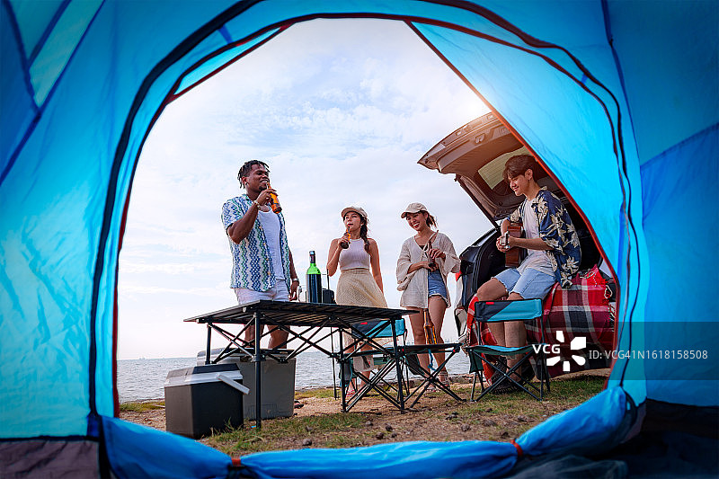 一群青少年在海滩上玩耍和弹吉他，露营，旅行概念图片素材