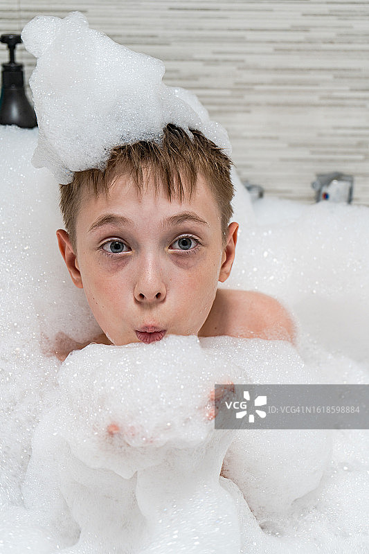 男孩在泡泡浴中吹肥皂泡图片素材