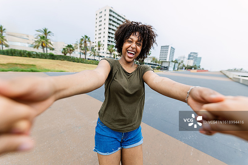POV视角：年轻非裔美国少女在城市街道上手牵手奔跑嬉戏图片素材