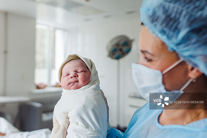 尽职的产科护士温柔地抱着襁褓中的男婴图片素材