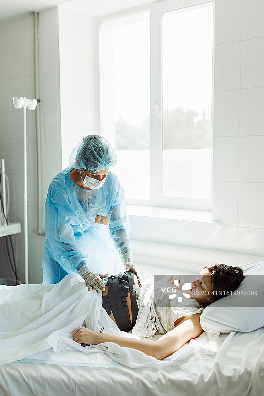 孕妇躺在床上，用现代设备监测胎儿心跳，女医生轻轻触摸肚子图片素材