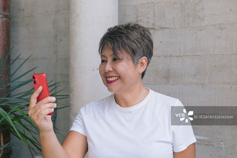 面带微笑的漂亮女商人在办公室背景上使用手机。站在户外时用电话交谈的时尚办公室服装。库存照片图片素材