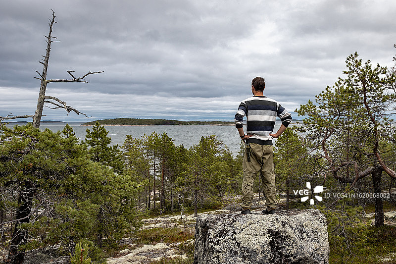 穿条纹毛衣男人森林大石上眺望湖泊岛屿图片素材