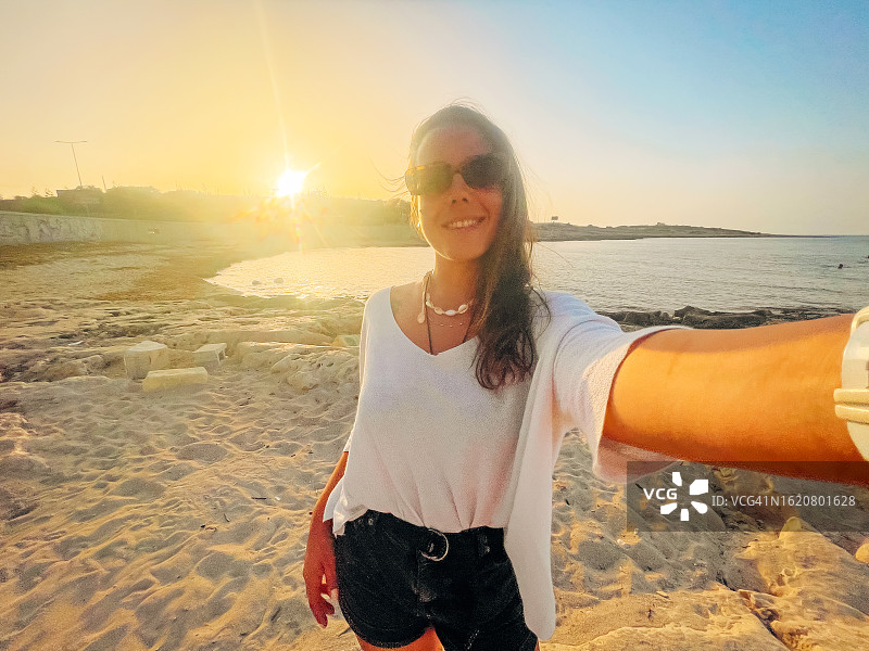 微笑的妇女享受假期，在海滩自拍图片素材