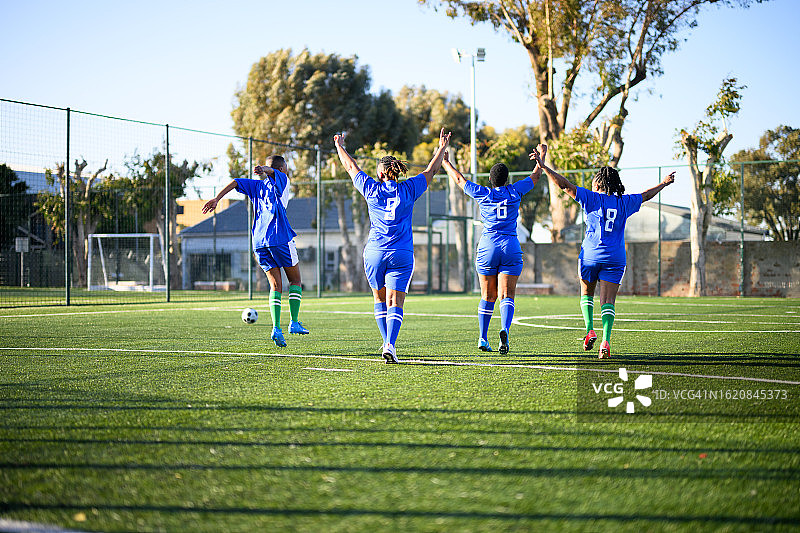 兴奋地在球场上奔跑庆祝的女子足球运动员图片素材