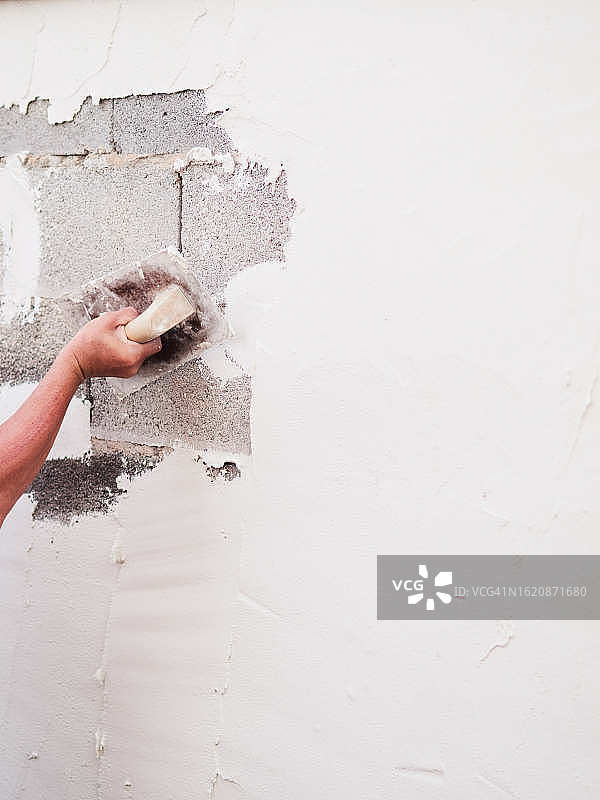 工人在墙上抹白水泥建造房屋的手部特写图片素材