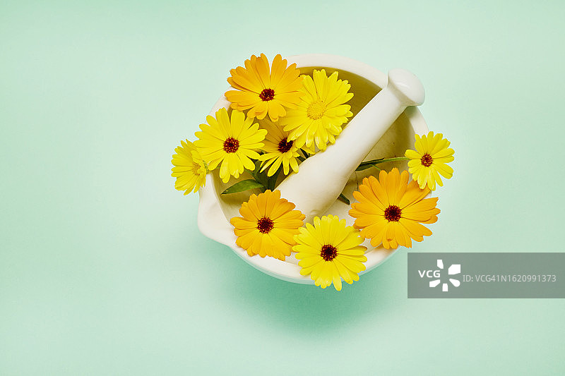 绿松石背景白色研钵中的金盏花图片素材