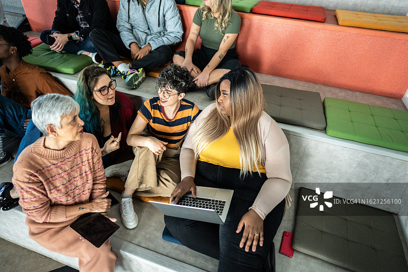 在礼堂开会时交谈并使用笔记本电脑的女商人图片素材