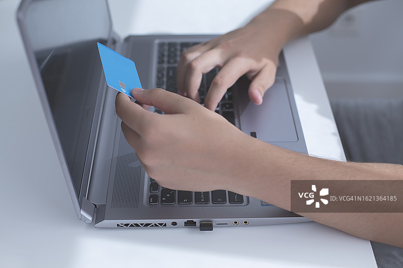 男人使用笔记本电脑并拿着信用卡图片素材