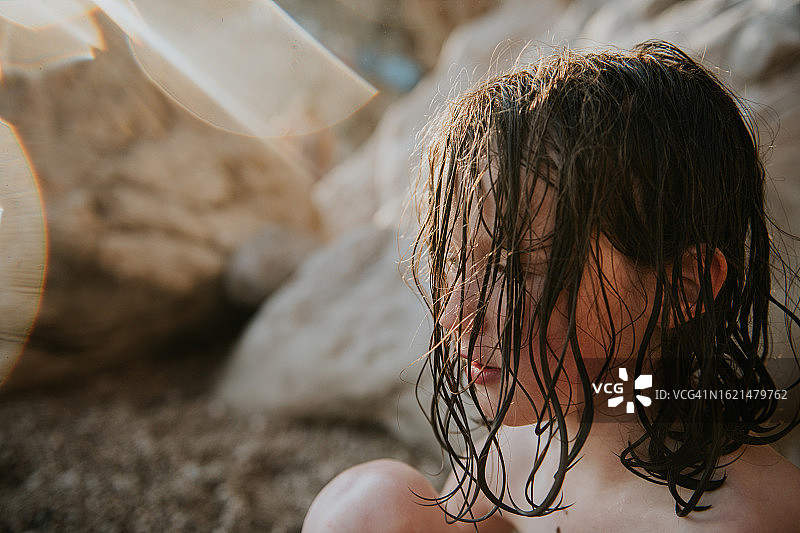 傍晚沙滩上湿发遮脸的儿童，夕阳逆光图片素材
