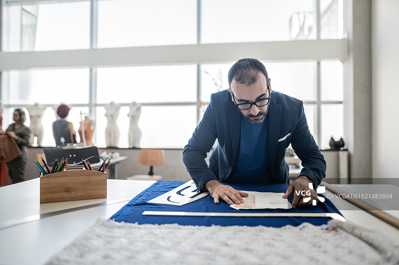 在工作室工作的中年裁缝/时装设计师图片素材