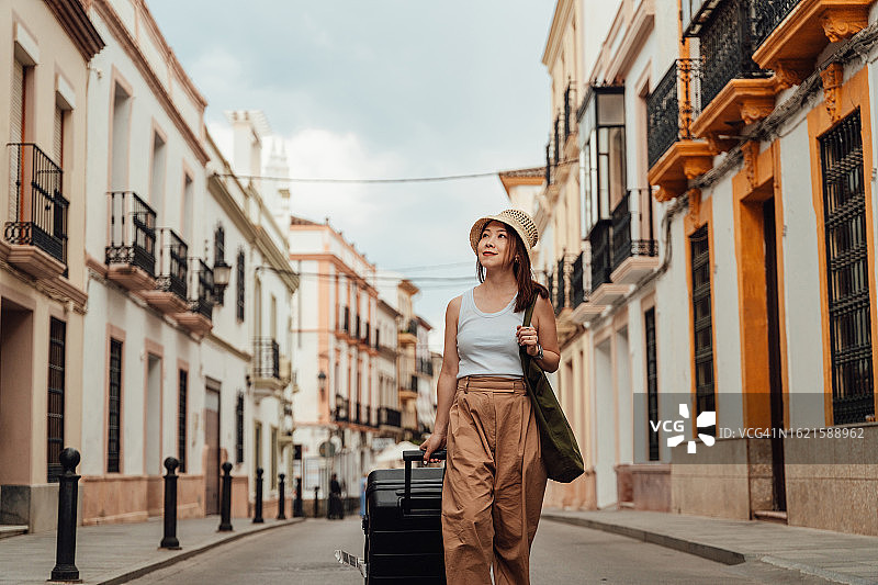 年轻的亚洲女游客携带行李走在街上图片素材
