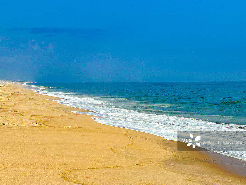 彼得斯塘池塘海滩的金色沙滩、白色海浪和蓝色大西洋图片素材
