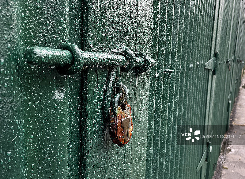 带生锈挂锁和雨滴的绿色棚屋螺栓图片素材