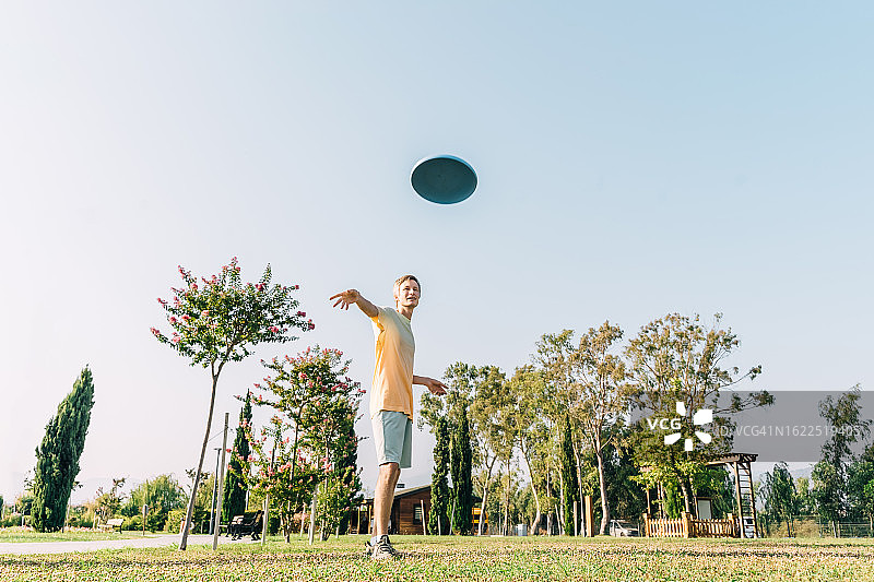 年轻男人在阳光明媚的夏日公园里玩飞盘图片素材