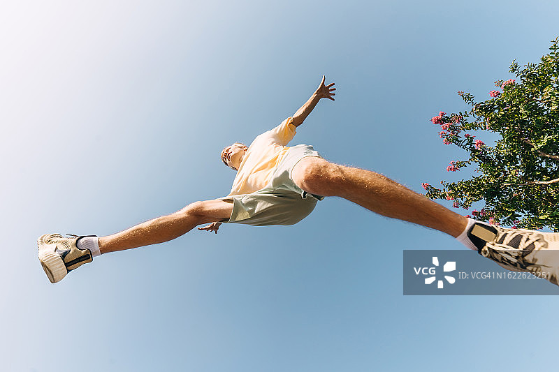 在蓝天背景下跳跃的男人（仰视）图片素材