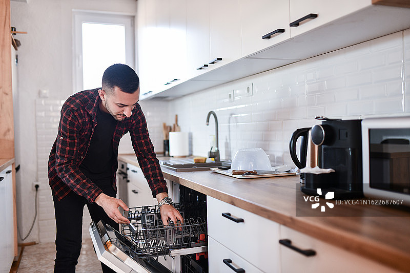 穿格子衬衫的细心男人认真洗碗图片素材
