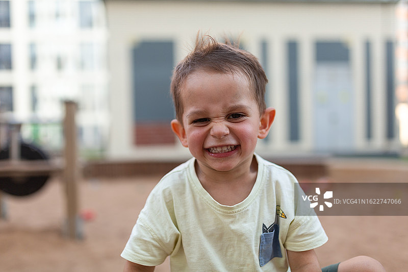 在户外玩耍并看着镜头的快乐小男孩图片素材