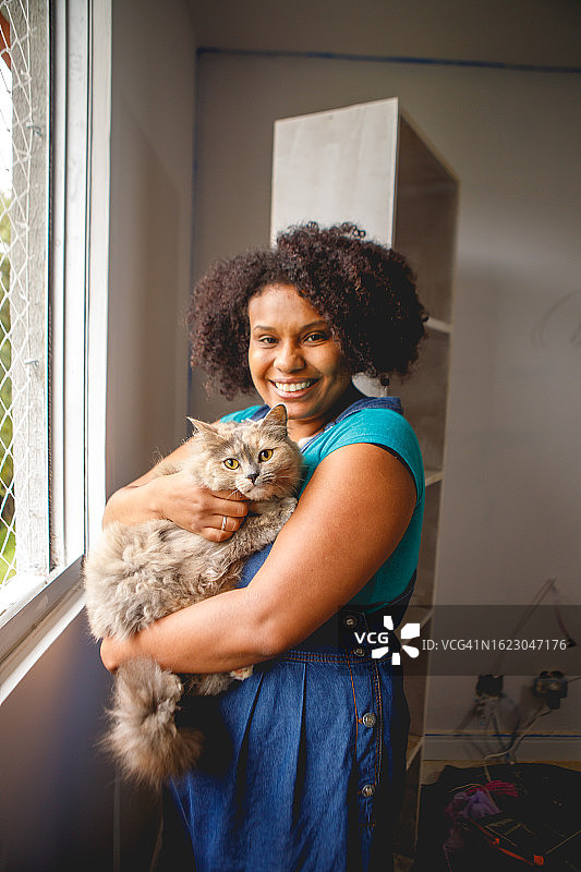 在家居装修中休息并抚摸宠物的黑人女性肖像图片素材