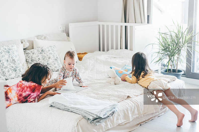 姐妹俩在家里床上一起读书，享受家庭时光，姐妹情深。图片素材