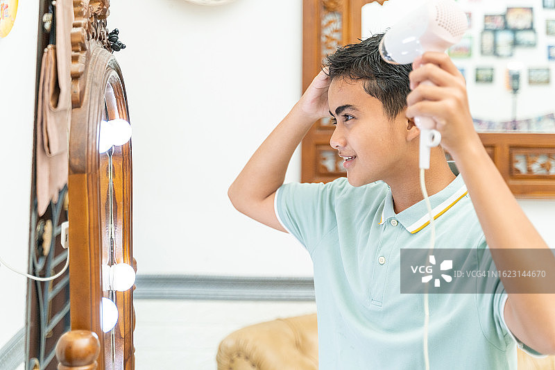 对着镜子吹头发的青少年男孩图片素材