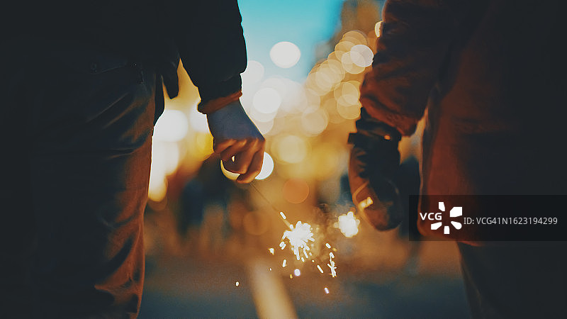 在阿姆斯特丹夜晚庆祝圣诞的情侣，身着暖和的衣服，手持烟花图片素材