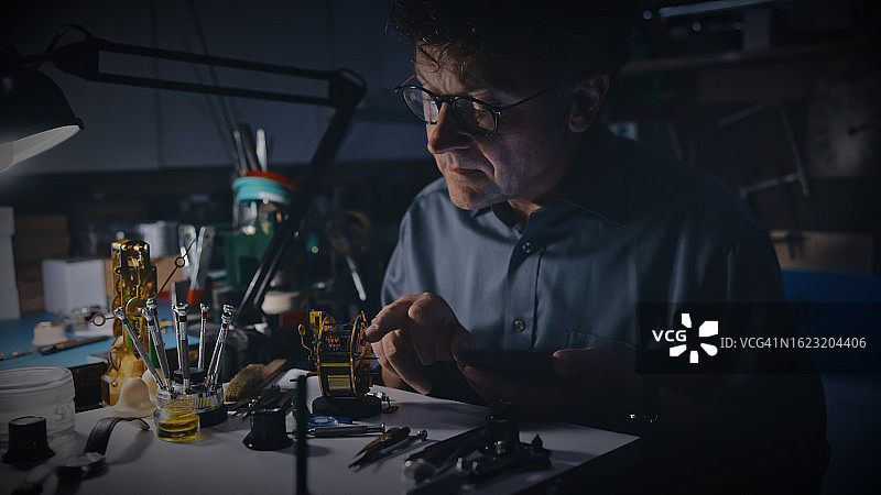 专注工匠在维修店检查钟表齿轮图片素材