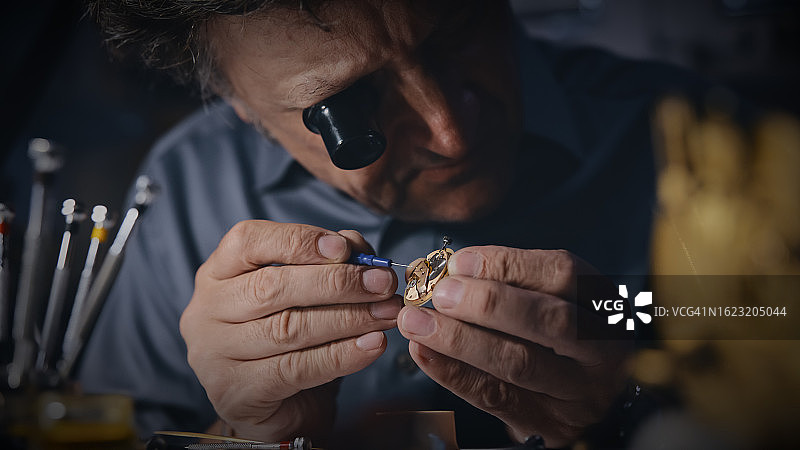 戴着放大镜修理齿轮的中年工匠图片素材