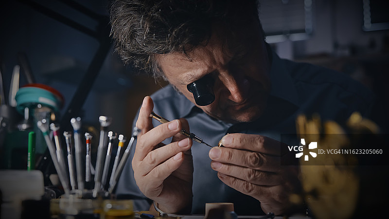 工匠在工作场所戴着放大镜修理齿轮图片素材