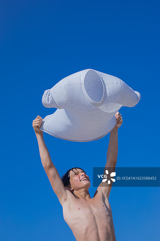 释放想象力：少年将T恤变成降落伞，探索天空图片素材