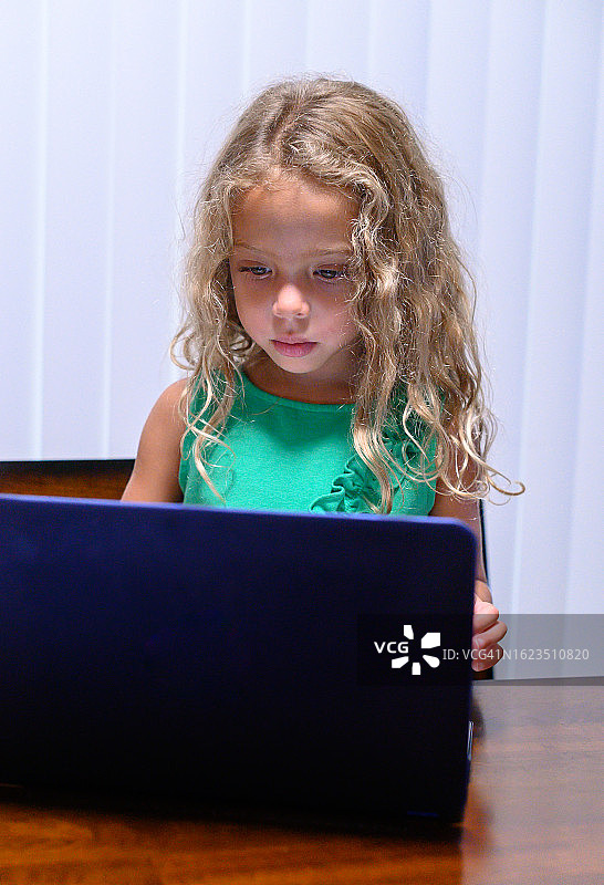 在室内使用笔记本电脑的可爱混血四岁女孩图片素材