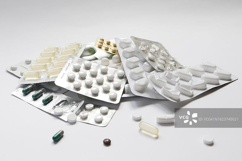 药物滥用、成瘾的象征性图像，各种药丸和泡罩包装的特写，白色背景，德国图片素材