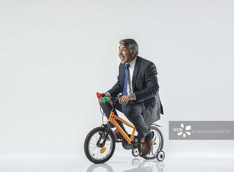 在白色背景上骑自行车的快乐年长男商人图片素材