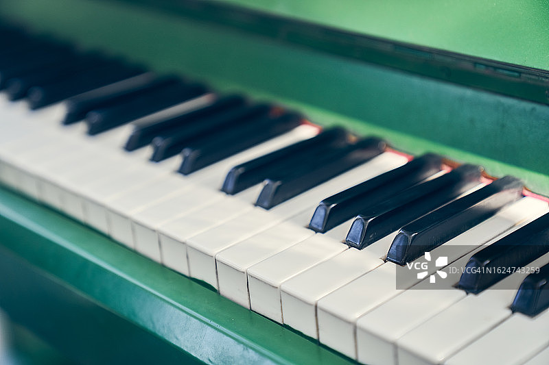 绿色钢琴背景，阳光下的键盘乐器，留白区域图片素材