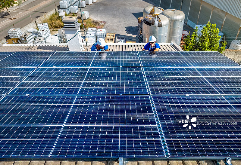 专业技术人员在阳光下检查安装太阳能屋顶电池板图片素材