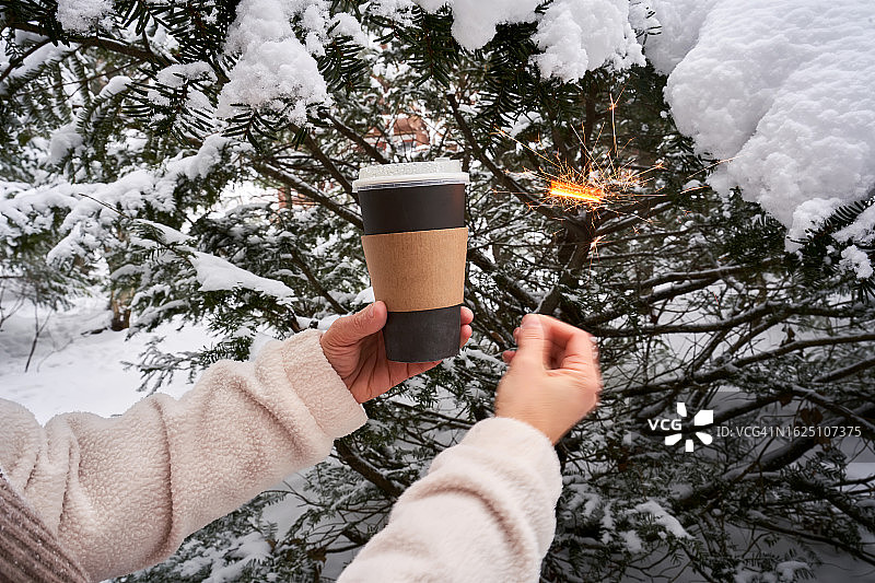 雪冬森林背景下的外带咖啡杯和烟花棒。图片素材