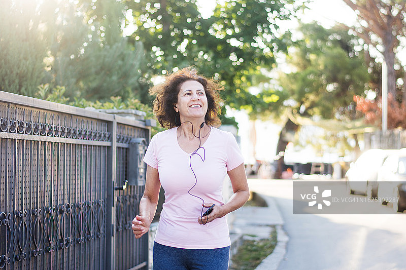 戴着耳机跑步的活跃中年妇女图片素材