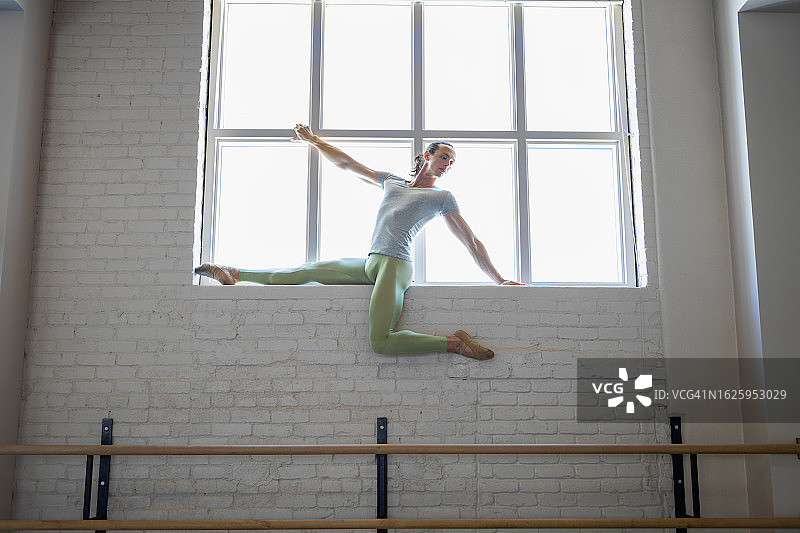 男人在芭蕾舞工作室里爬上窗台图片素材
