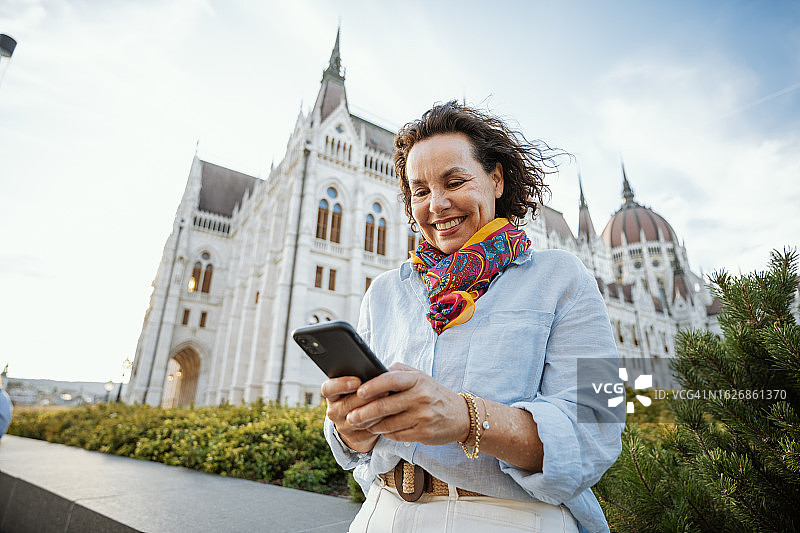 在夏天游览城市并使用智能手机的成熟拉丁裔迷人女性肖像图片素材