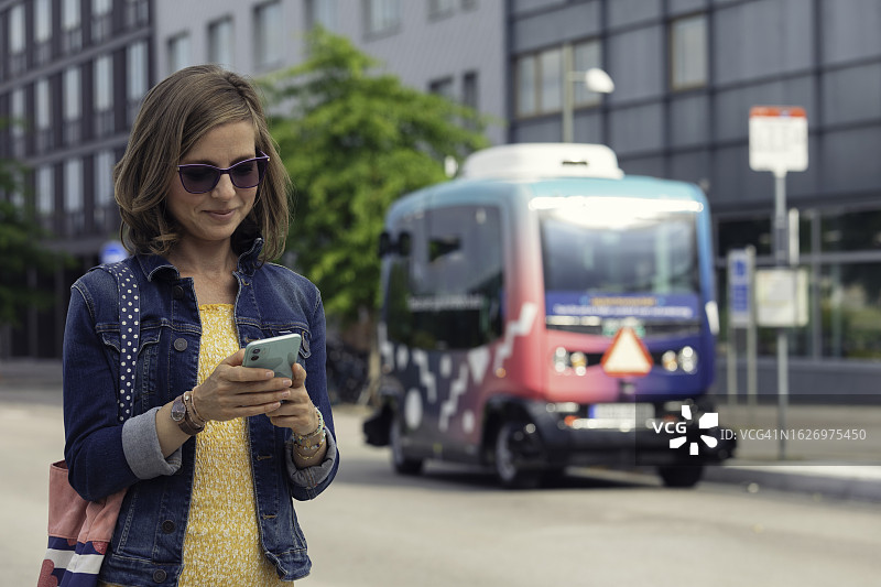 女人使用手机App预订无人驾驶巴士图片素材