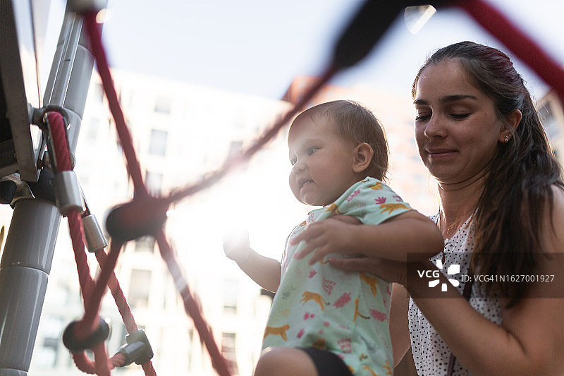 母亲教女儿在游乐场爬绳网图片素材