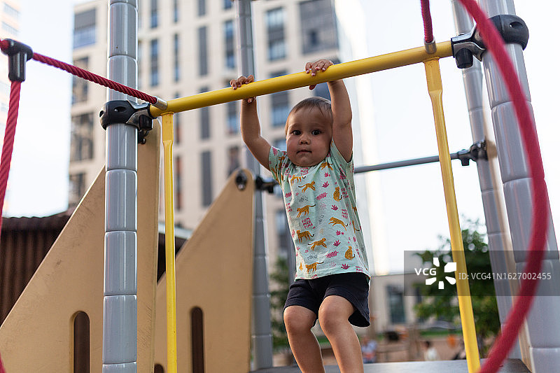 在游乐场单杠上看向镜头的小女孩图片素材