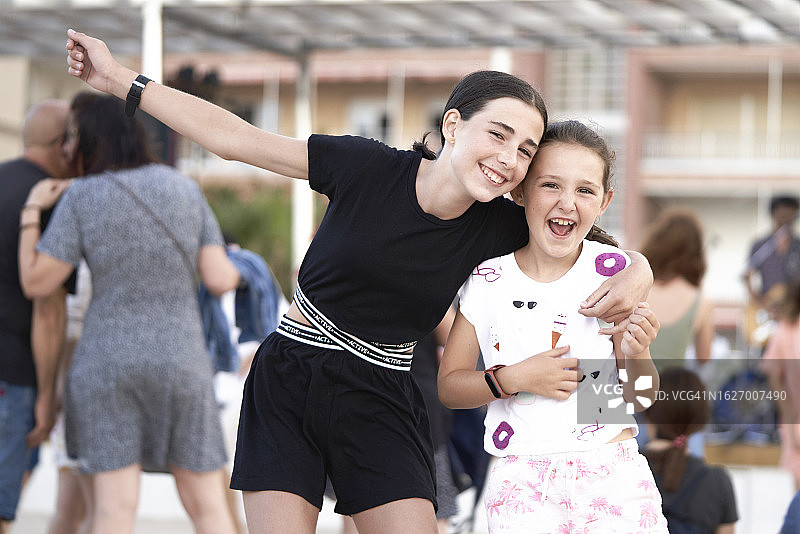 两个小女孩在城市户外对着镜头微笑拥抱图片素材