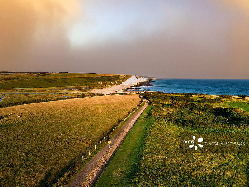 英格兰南部海岸七姐妹悬崖上，男人在小路上徒步旅行的航拍图片素材