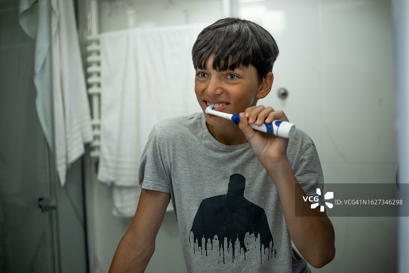 青少年在浴室里用新式电动牙刷刷牙图片素材