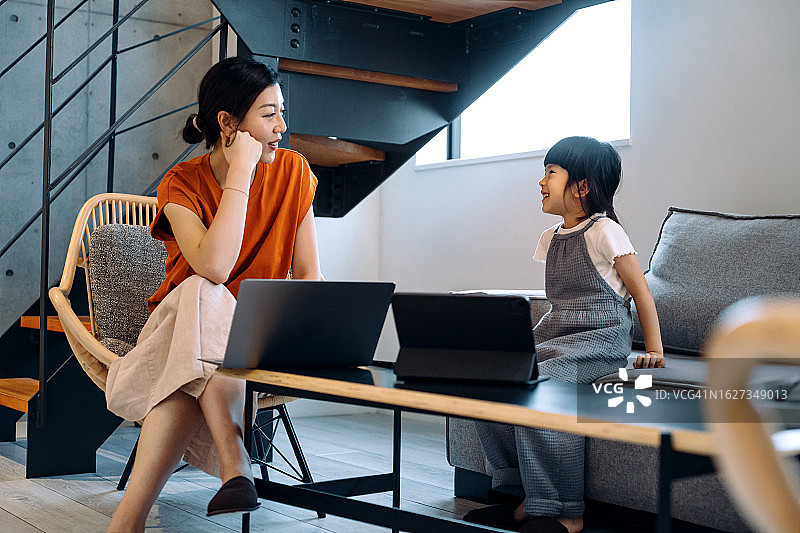 年轻的亚洲母女在家中使用笔记本电脑和数位板图片素材