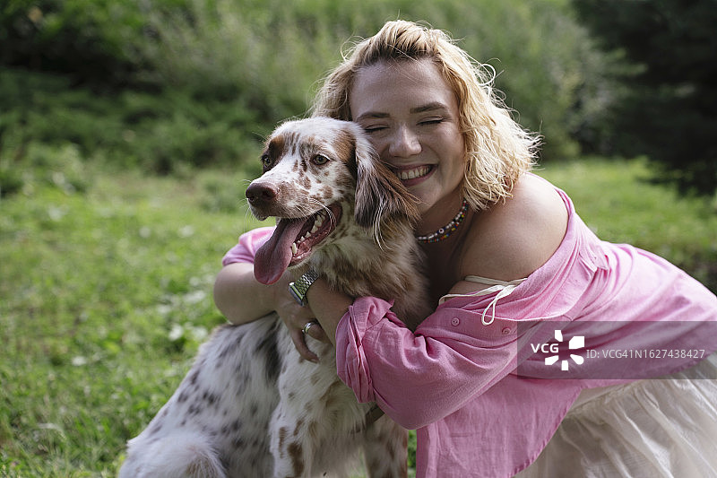 快乐的女人在公园里拥抱狗图片素材